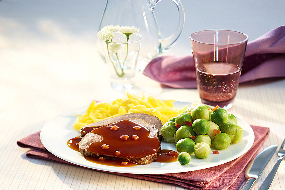 Ein gedeckter Tisch mit Rinderbraten, Spätzle und Rosenkohl.