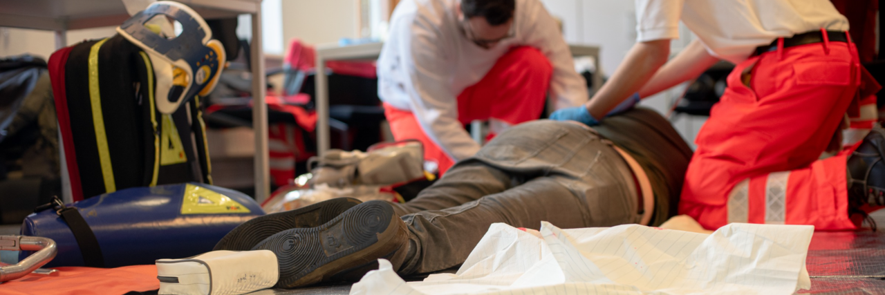 2 Menschen in Einsatzkleidung legen eine Person in stabile Seitenlage