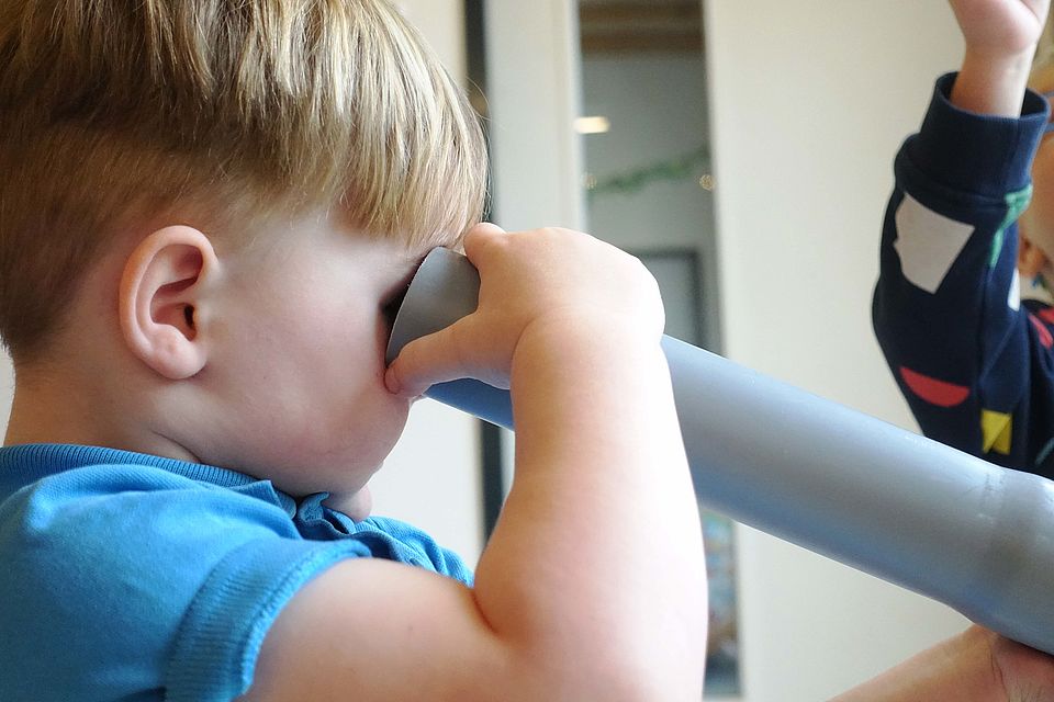 kleiner Junge schaut durch ein selbstgebautes Fernrohr