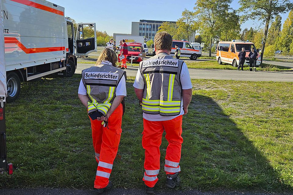 2 Einsatzkräfte mit Schiedsrichterwesten laufen über eine Wiese