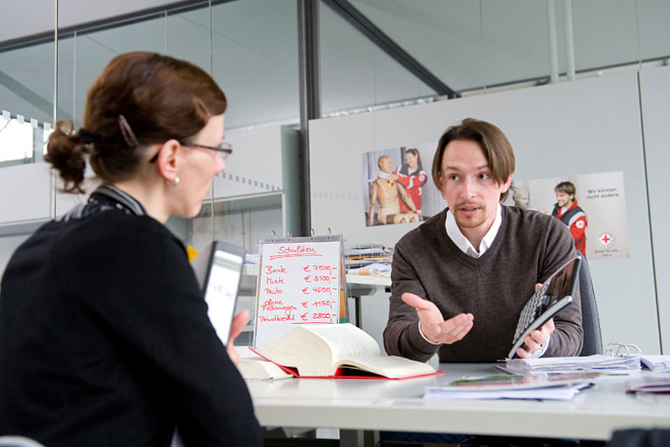 Mann sitz Frau am Tisch gegenüber, beide sprechen miteinander