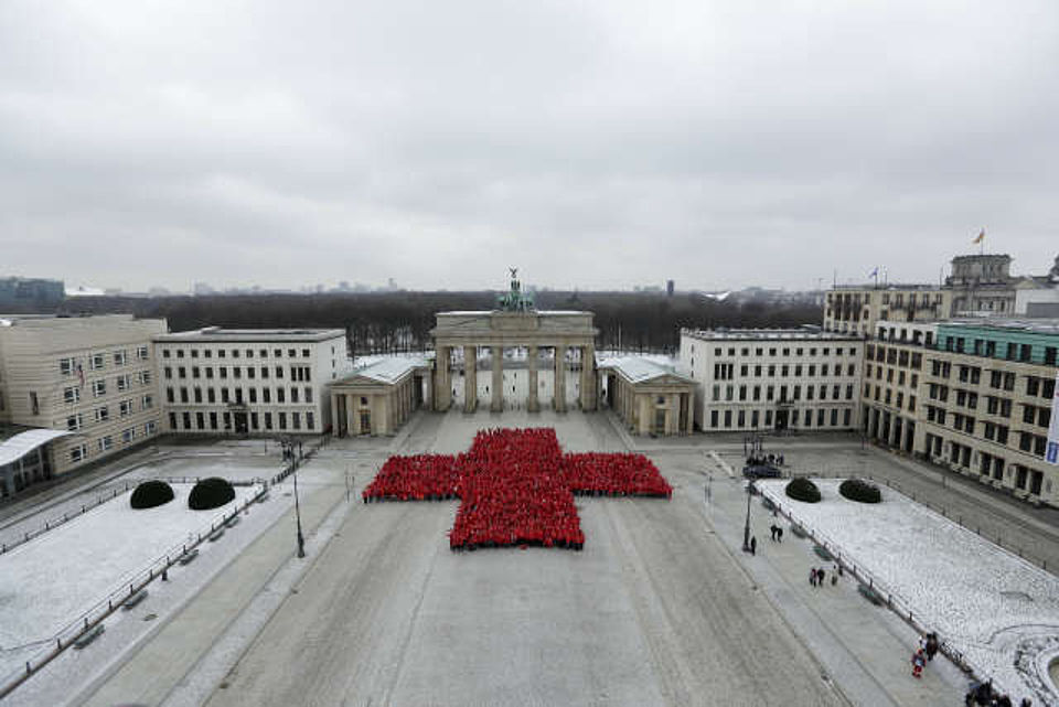 viele Menschen formen vor dem Brandenburger Tor ein Rotes Kreuz