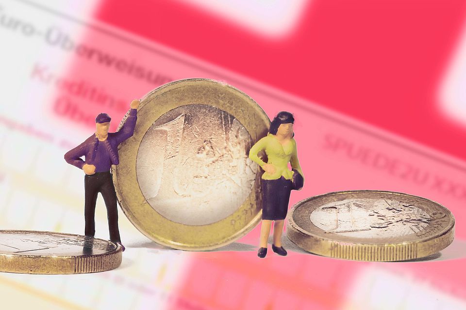 Zwei Miniaturfiguten stehen zwischen zwei Euro-Münzen