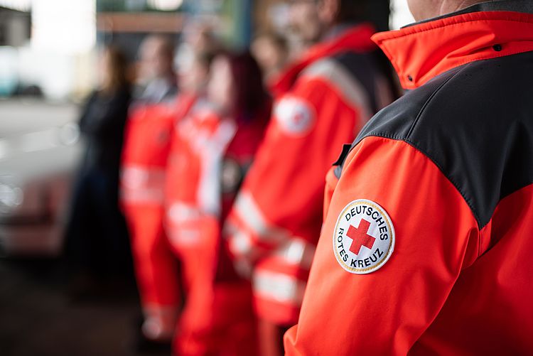 Menschen in DRK-Einsatzkleidung stehen hintereinander