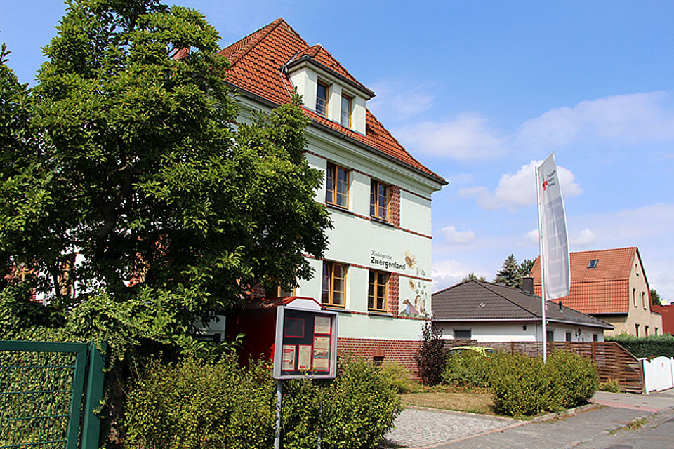 zweistöckige Villa mit altem Baumbestand davor