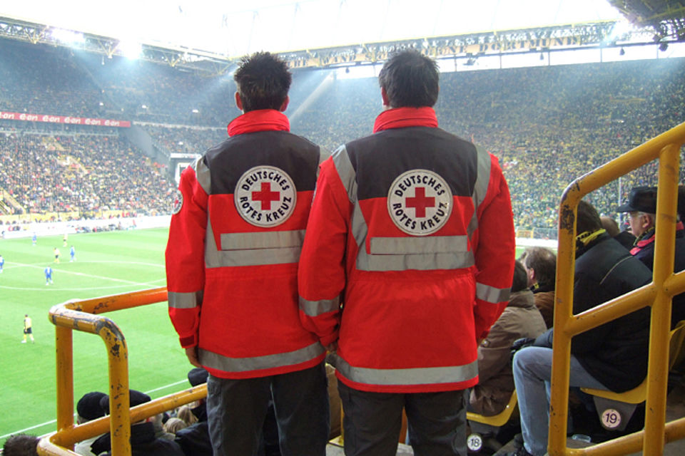 2 Einsatzkräfte schauen im Stadion einem Fußballspiel zu