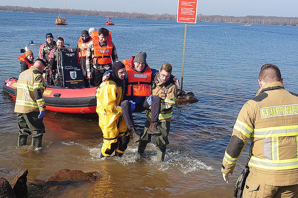 Passagier wird von Feuerwehrleuten an Land getragen