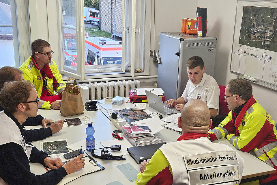 mehrere Personene der Einsatzleitung sitzem am Tisch bei einer Besprechung